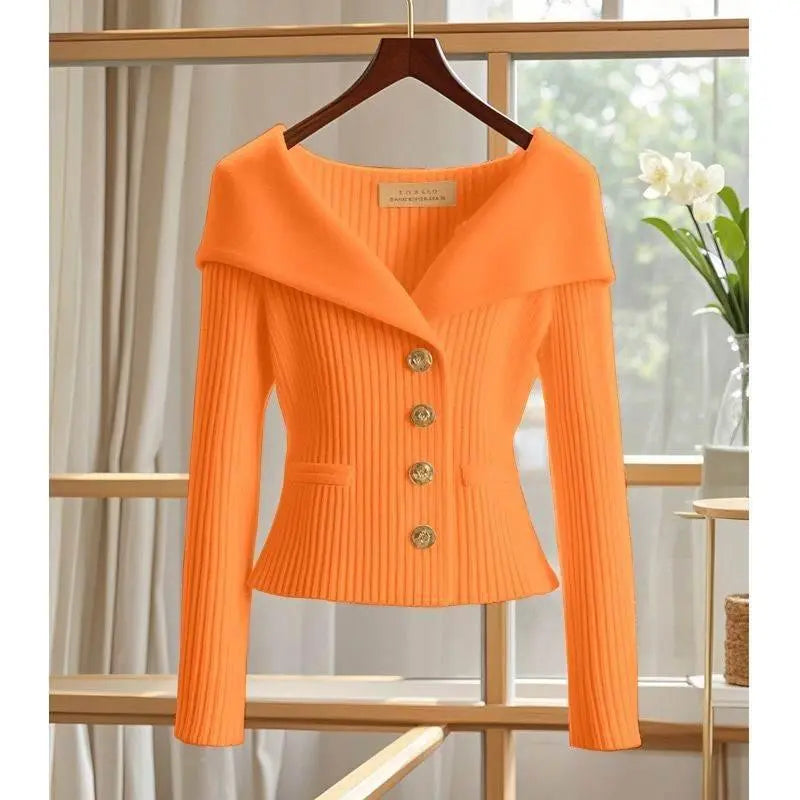 Orange ribbed knit women's blazer with wide collar and gold buttons, hanging indoors
