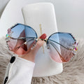 Sunglasses with colorful embellishments held in front of a Sungia branded box.