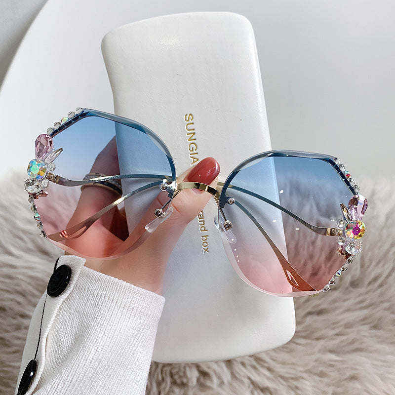 Sunglasses with colorful embellishments held in front of a Sungia branded box.